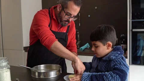 Dad teaching his kid to make the traditional family cookies recipe at home 스톡 동영상 346775500