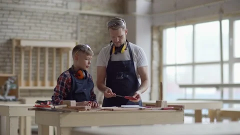 Dad teaching son how to use chisel and ruler at carpentry Stock Footage 142164274