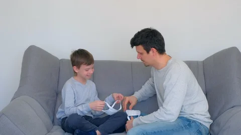 Dad is teaching son putting on mask on face, coronavirus pandemic quarantine. Stock Footage 128975122
