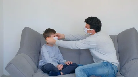 Dad is teaching son putting on mask on face, coronavirus pandemic quarantine. Stock Footage 128975235