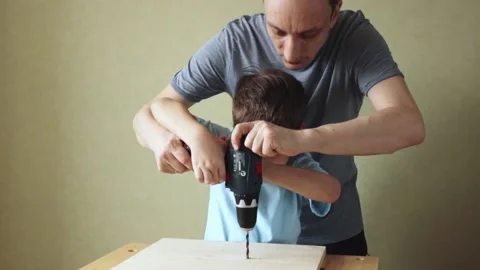 Dad teaching son work with drill while standing at workbench Stock Footage 157671727