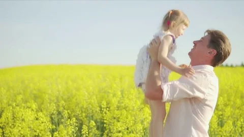 Dad throws a daughter on a rapeseed field Stock Footage 76202332