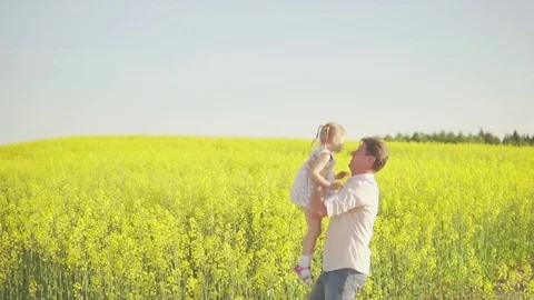 Dad throws a daughter on a rapeseed field Stock Footage 76202356