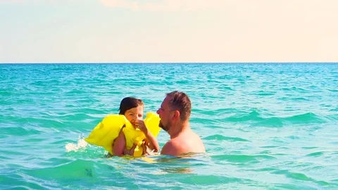 Dad throws up his son in an inflatable life jacket in the sea. Safety Concerns a Stock Footage 105918753