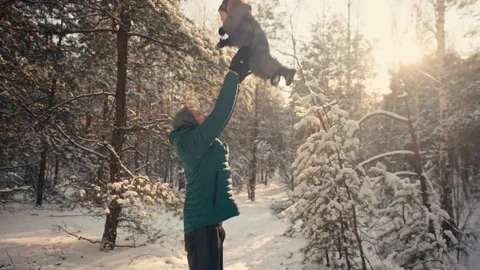 Dad throws up to the sky little boy in the winter forest on the background of Stock Footage 167954371