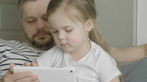 Dad tries not to sleep while playing with his daughter. Funny games app. 库存影片 131937783