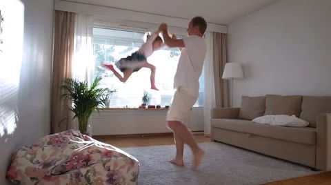 Dad turns and throws up a small daughter on hands in the Sunny room. Slow motion Stock Footage 67860382