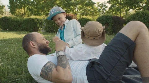 Dad with two sons playing in nature, laughing pampering on the grass Vídeo Stock 89947856