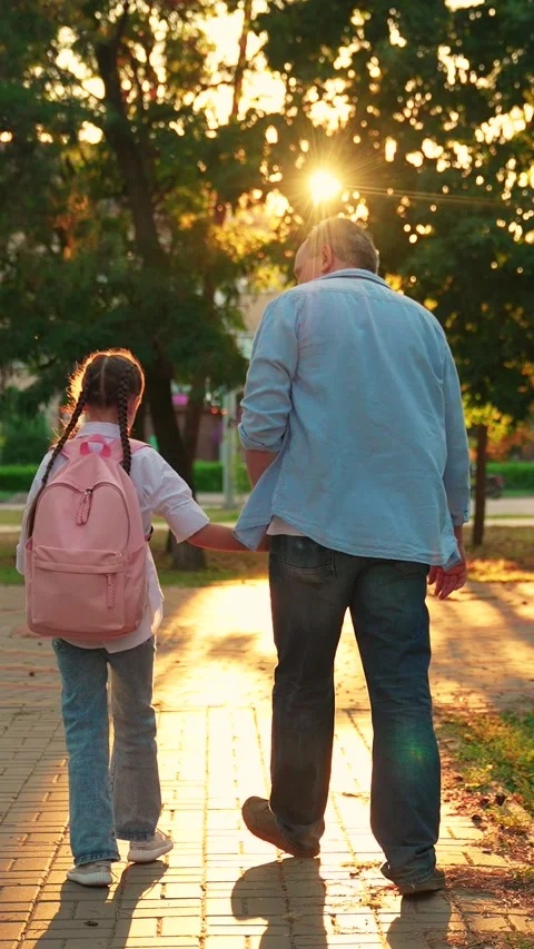 Dad walks kid with backpack to school for classes along city street. Parent Stock Footage 319798499