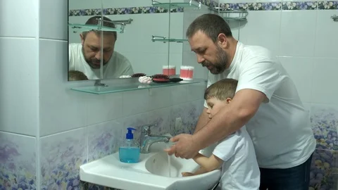 Dad washes a small child's hands with soap over the sink with running water. Stock Footage 128336574