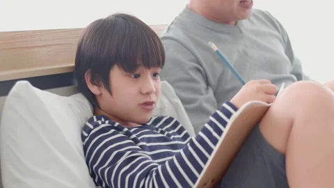 Dad working on laptop and talking his curious little son as writing on notebook Stock Footage 142869819
