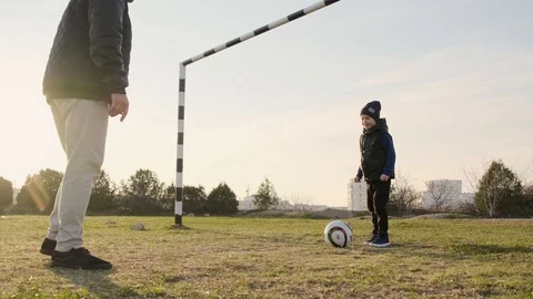 Daddy and son have fun playing soccer outdoors in spring on sunset slow motion Stock Footage 111432243