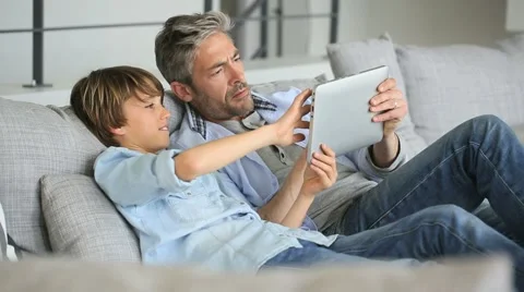 Daddy and son websurfing on digital tablet at home Video stock 48758767