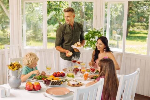 Daddy bringing some bread while having family lunch outside Foto stock