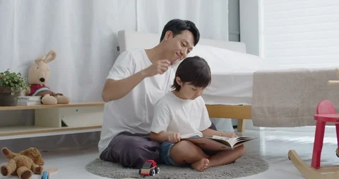 Daddy brushes his daughter's head reading a storybook Stock Footage 100935792
