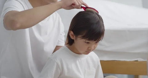 Daddy brushes his daughter's head reading a storybook Stock Footage 100946768