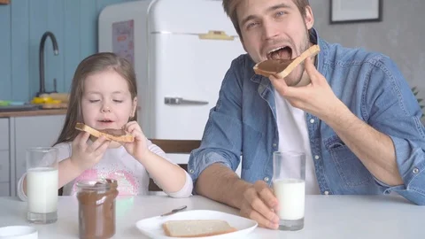 Daddy with daughter having breakfast at the kitchen table and laughing Stock Footage 123916405