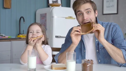 Daddy with daughter having breakfast at the kitchen table and laughing Stock Footage 123916406