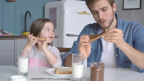 Daddy with daughter having breakfast at the kitchen table and laughing Stock Footage 123916410