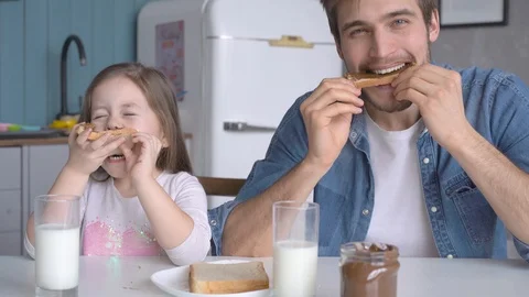Daddy with daughter having breakfast at the kitchen table and laughing Stock Footage 123916413