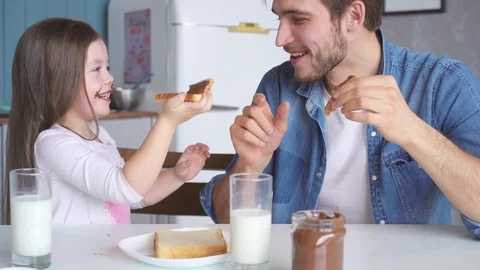 Daddy with daughter having breakfast at the kitchen table and laughing Stock Footage 123916415