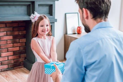 Daddy giving present box to his small girl at home Stock Photos