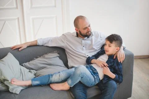 Daddy with son relaxing on sofa. Stock Photos