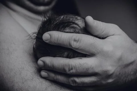 Daddy's gentle hand holds a small baby's head Stock Photos