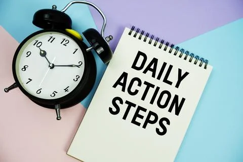 Daily Action Steps text written on notepad with alarm clock flat lay on mul.. Stock Photos
