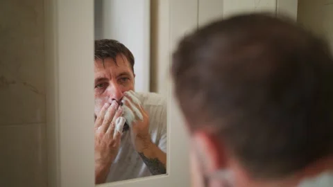 Daily morning routine of man applying shaving foam on his face, looking at .. Stock Footage 343418253