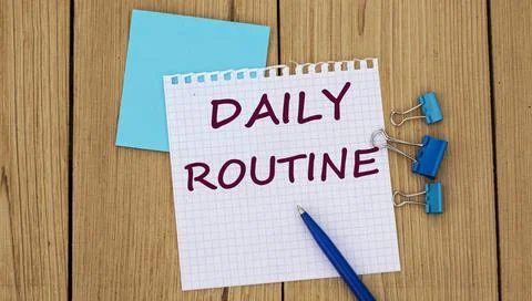 DAILY ROUTINE - word written in a notebook on a wooden background with a pen Stock Photos