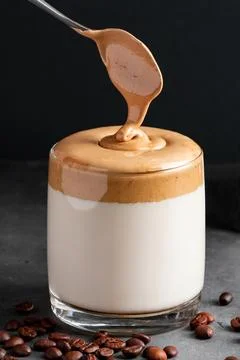 Dalgona coffee on a black background. The process of making a trendy drink... Stock Photos