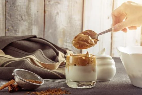 Dalgona coffee, process of making, forming layers coffee on gray kitchen tabl Foto stock
