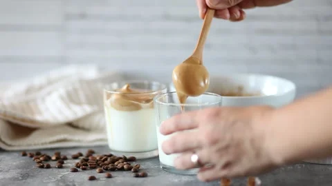 Dalgona Coffee. Woman hand put whipped coffee in the glass Stock Footage 133646053