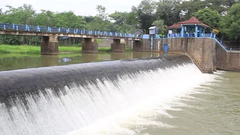 Dam with cascading waterfall and stone embankments, and a traditional Vidéo 302334511