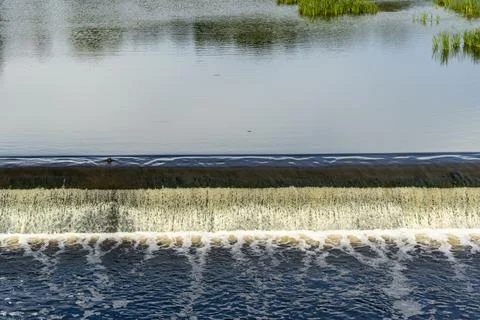 Dam on a small river. Water flows from a small river dam, boils, foams Stock Photos