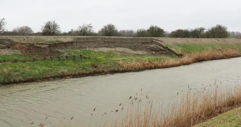 Damage caused by slumping to a flood barrier on the Sixteen Foot Drain near M Stock Footage 286204454