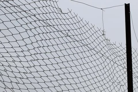 Damaged barbed wire chain link fence Stock Photos