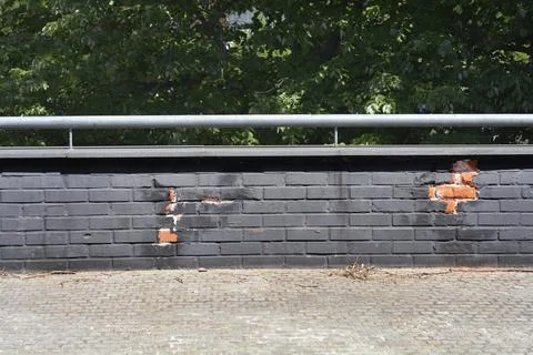 Damaged black painted brick wall with railing Stock Photos