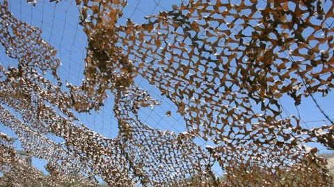 Damaged camo netting in front of blue sky. view of the sky through a camouflage  스톡 동영상 155865147