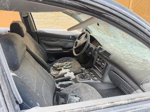 Damaged car interior featuring shattered windshield, scattered glass debris.. Stock Photos