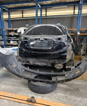 Damaged car undergoing rear bumper repair in workshop Фото