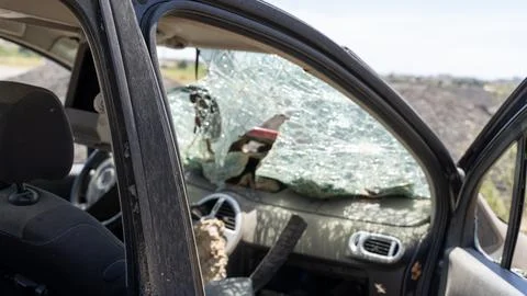 Damaged compact car interior with open front door, shattered windshield Photos