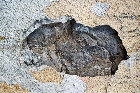 Damaged concrete wall texture with peeling paint and large hole showing round Stock Photos