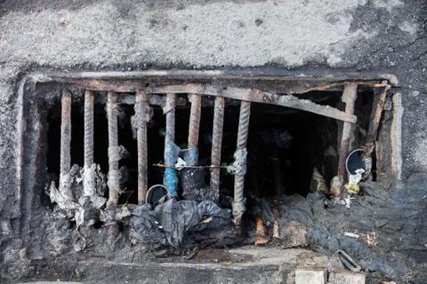 Damaged drain grate with the garbage Stock Photos