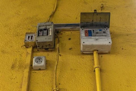 A damaged electrical socket on a dirty yellow wall, damaged electrical inst.. Stock Photos