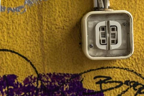 A damaged electrical socket on a dirty yellow wall, damaged electrical inst.. Stock Photos