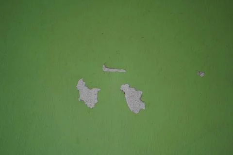 Damaged green wall texture with peeling paint and concrete patches in a rusti Stock Photos