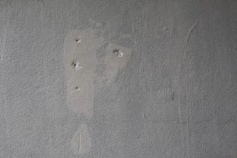 Damaged grey concrete wall with multiple impact holes and surface texture i.. Stock Photos