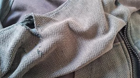 Damaged grey fabric featuring torn chevron pattern textile detail macro Stock Photos